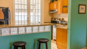 A kitchen with a window, wooden cabinets, and two stools.