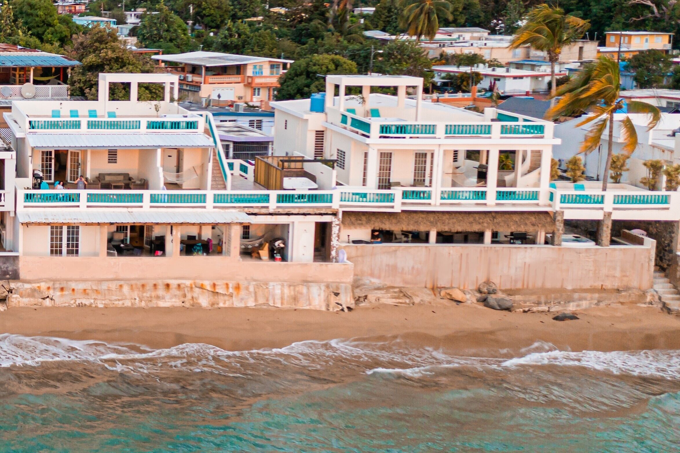 A beachfront property with multiple buildings, including a prominent white structure with balconies and a covered area.