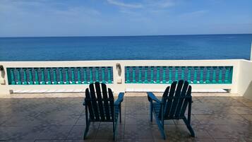 A terrace with two chairs facing a railing overlooking the sea.