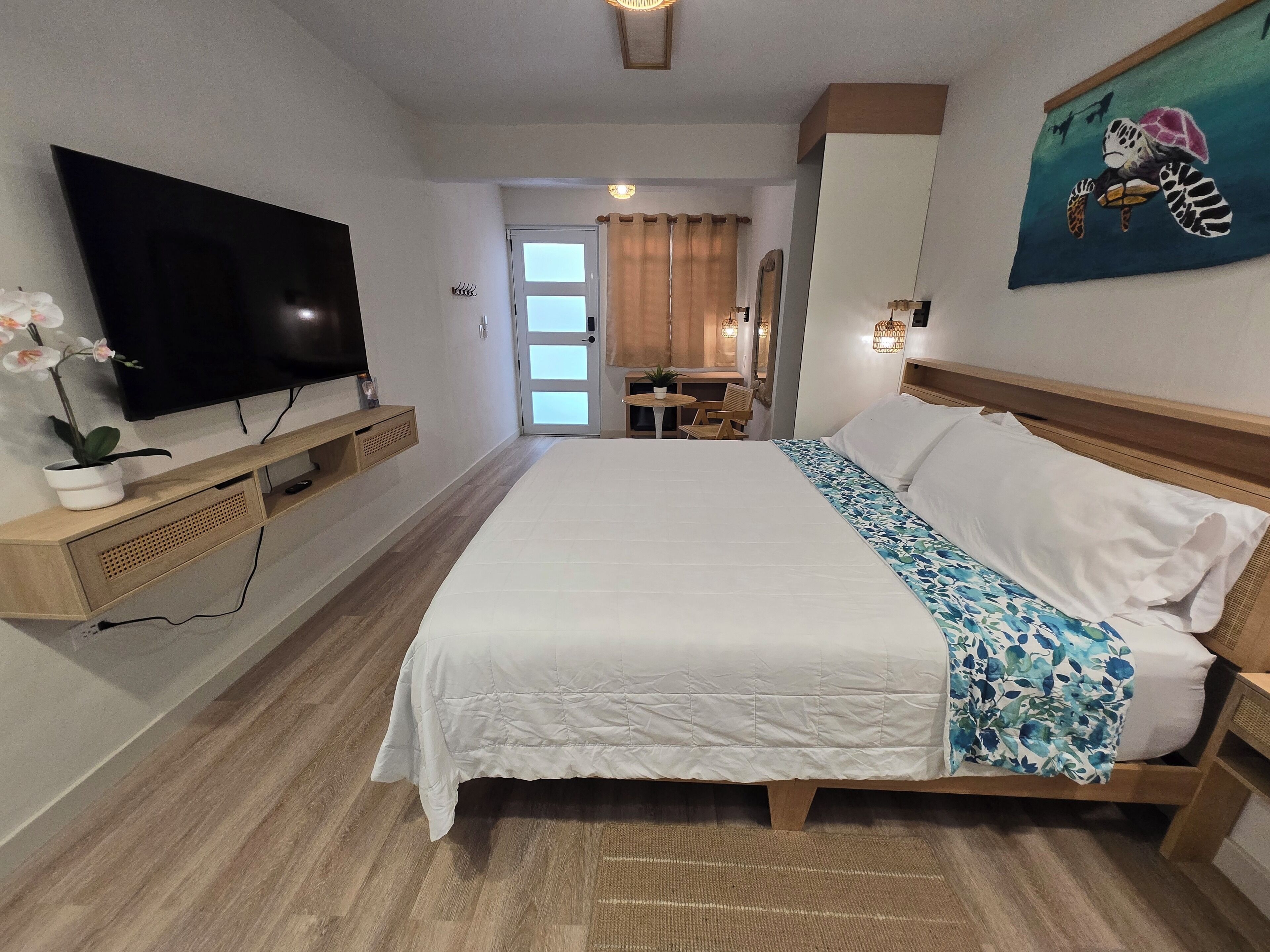 Een hotelkamer met een groot bed, een flatscreen televisie, een klein tafeltje en een stoel.