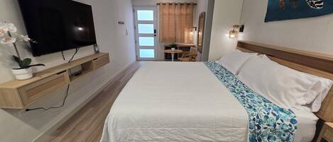 Een hotelkamer met een groot bed, een flatscreen televisie, een klein tafeltje en een stoel.