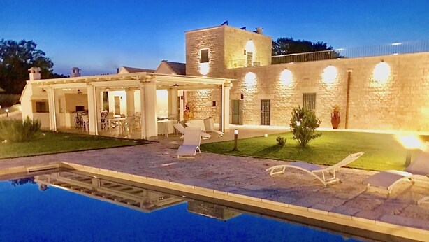 Una piscina con sillas de descanso y un área de terraza cubierta.