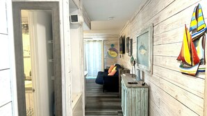 Un pasillo con paneles de madera, una escalera, una pequeña zona de estar con cojines y una pared decorada con motivos náuticos.