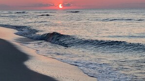 Una playa al atardecer con olas acercándose a la orilla.