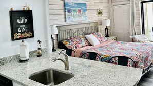 Una cocina moderna con encimera de granito, pileta de acero inoxidable y alacenas blancas.
