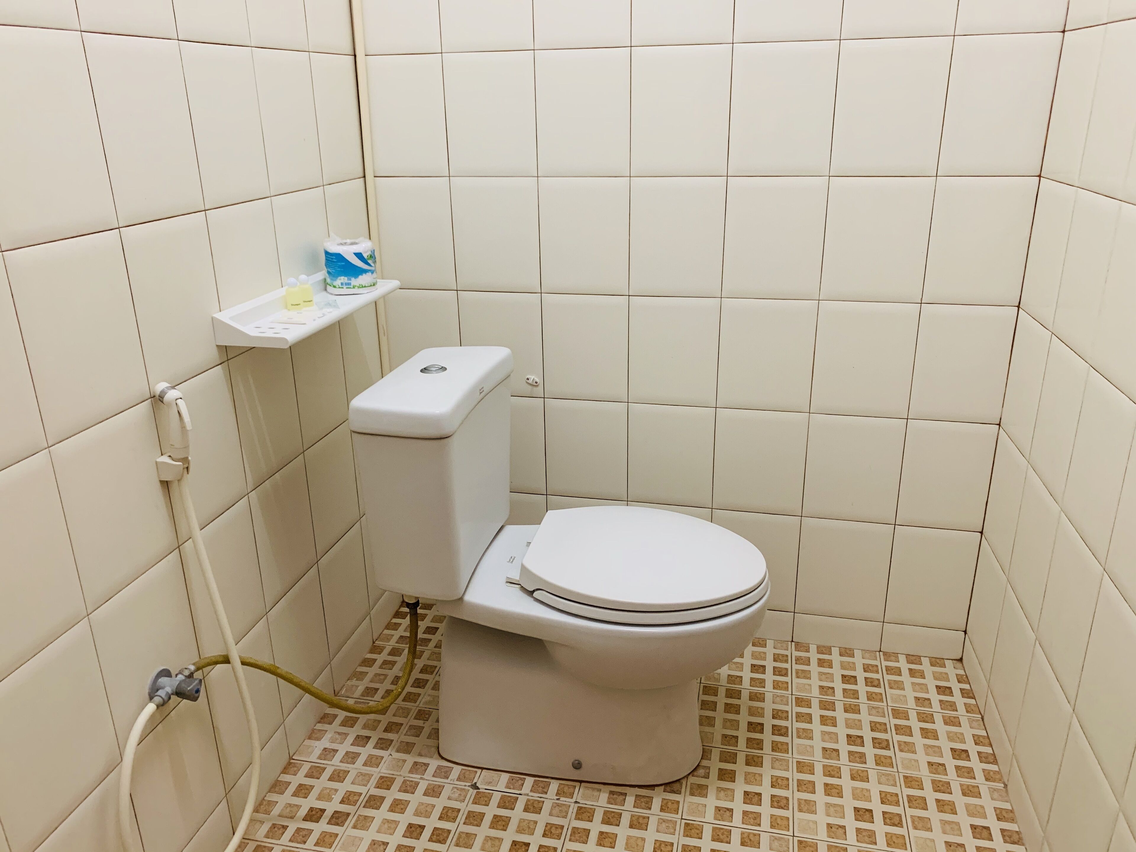 A small, tiled bathroom with a toilet, a sink, and a shower.