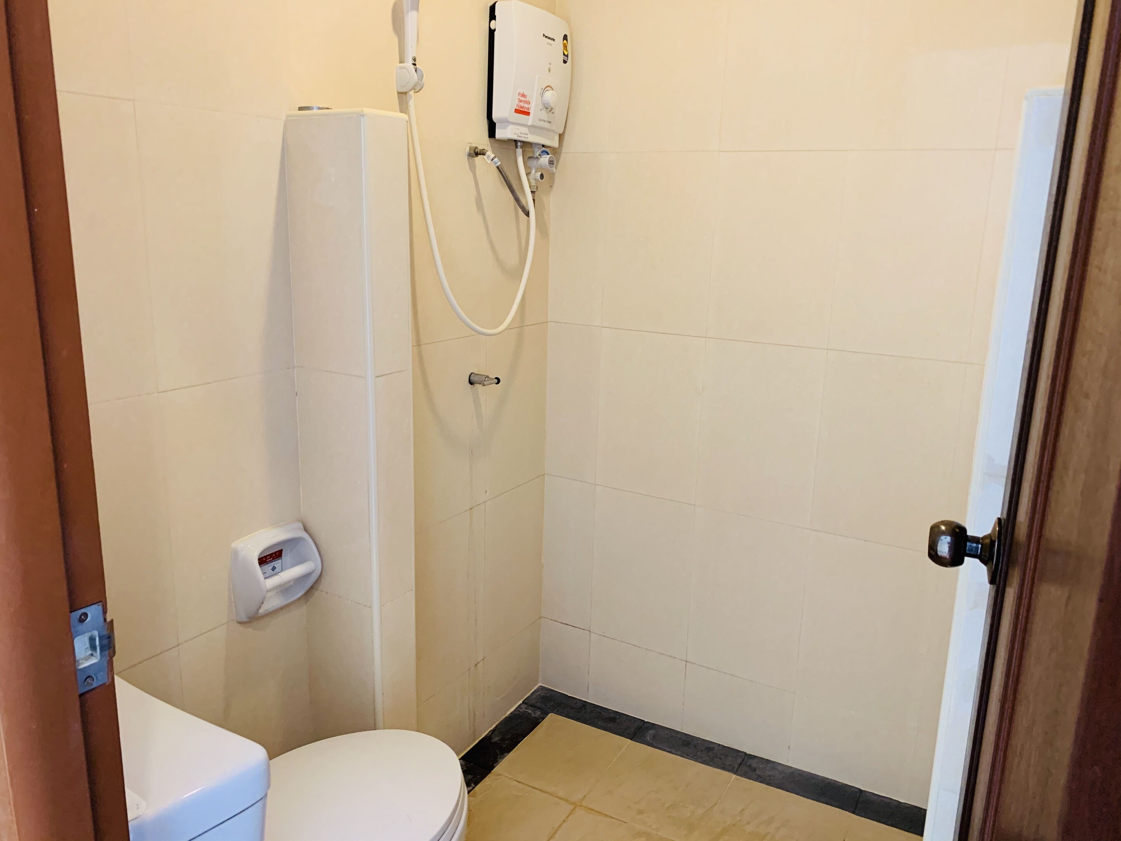 Un baño pequeño y limpio con inodoro, ducha y secamanos.