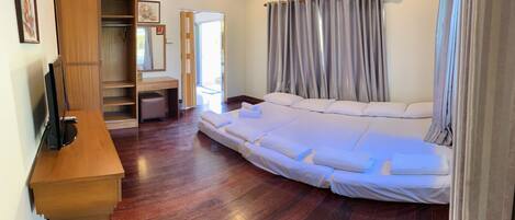 A bedroom with a large bed, wooden desk, and a wardrobe.