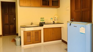 A kitchen with wooden cabinets, a sink, a coffee maker, and a refrigerator. - Srisupawadee Resort (Prachuap Khiri Khan)