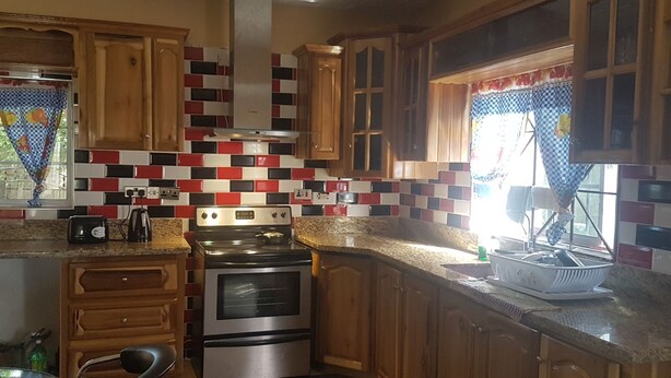 A kitchen with wooden cabinets, a stainless steel stove, and a tiled backsplash. - Relax and enjoy in this beautiful home in a quiet neighbourhood. (Mineral Hieghts)