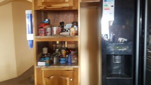 A kitchen with wooden cabinets, a black refrigerator, and a water dispenser. - Relax and enjoy in this beautiful home in a quiet neighbourhood. (Mineral Hieghts)