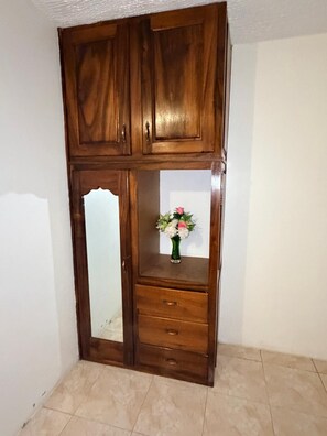 A wooden wardrobe with a mirror and a vase of flowers.