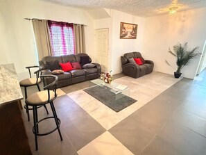A living room with a sofa, two armchairs, a coffee table, and a potted plant. - Relax and enjoy in this beautiful home in a quiet neighbourhood. (Mineral Hieghts)