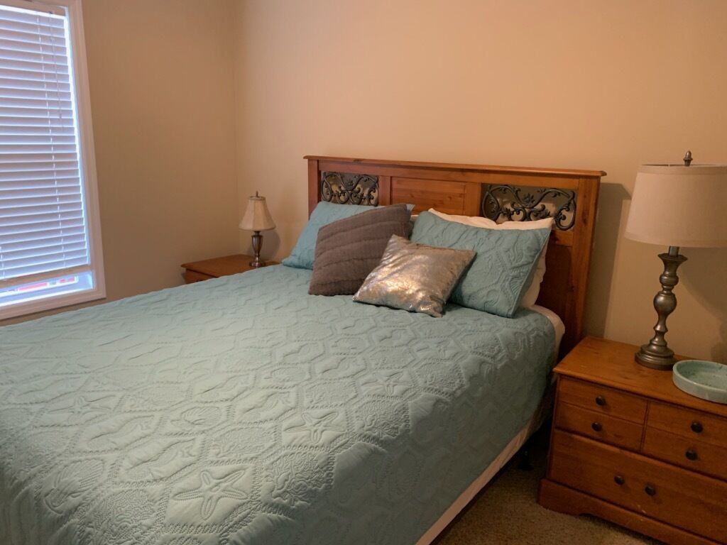 A bedroom with a bed, nightstands, and a lamp.