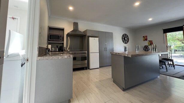A modern kitchen with a central island, built-in appliances, and a dining area with a view.