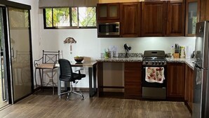 A compact kitchen with wooden cabinets, a microwave, a stove, and a refrigerator. - Villas Lambeau #2 - Ocean View - Fiber Optic / 1BR 1 BA (Uvita)