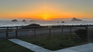 A coastal sunset view with a concrete pathway and a metal fence. - Oceanfront Retreat. Sunset Views. Whale Watching. Redwood Groves, 2 King Beds (Crescent City)