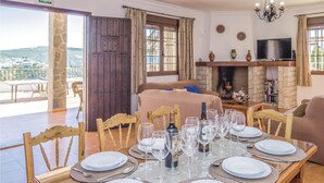 A dining area with a table set for a meal, a fireplace, and a bed in the background. - Lovely home in Iznájar (Iznájar)