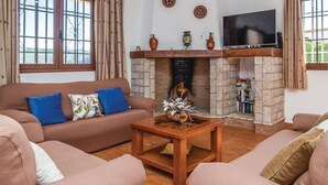 A living room with a brown sofa, a wooden coffee table, and a fireplace with bookshelves. - Lovely home in Iznájar (Iznájar)