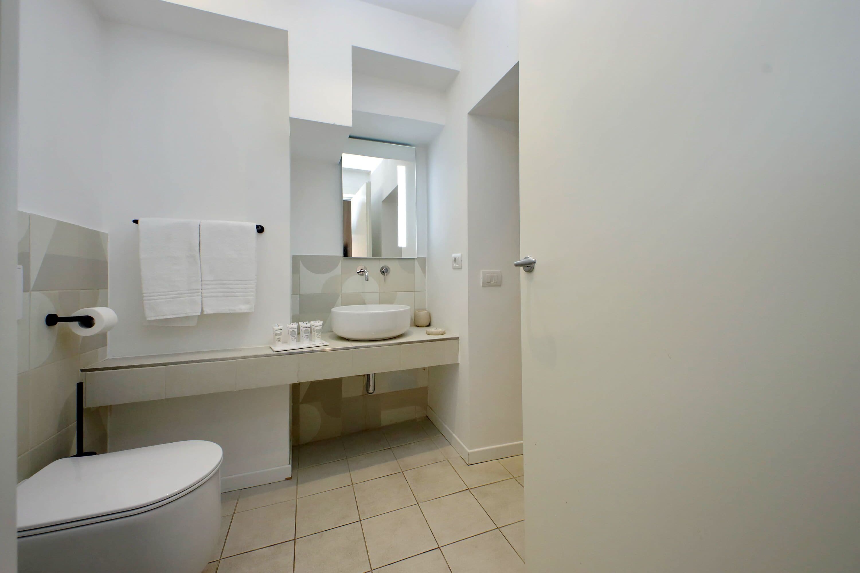 A modern bathroom with a toilet, sink, and mirror.