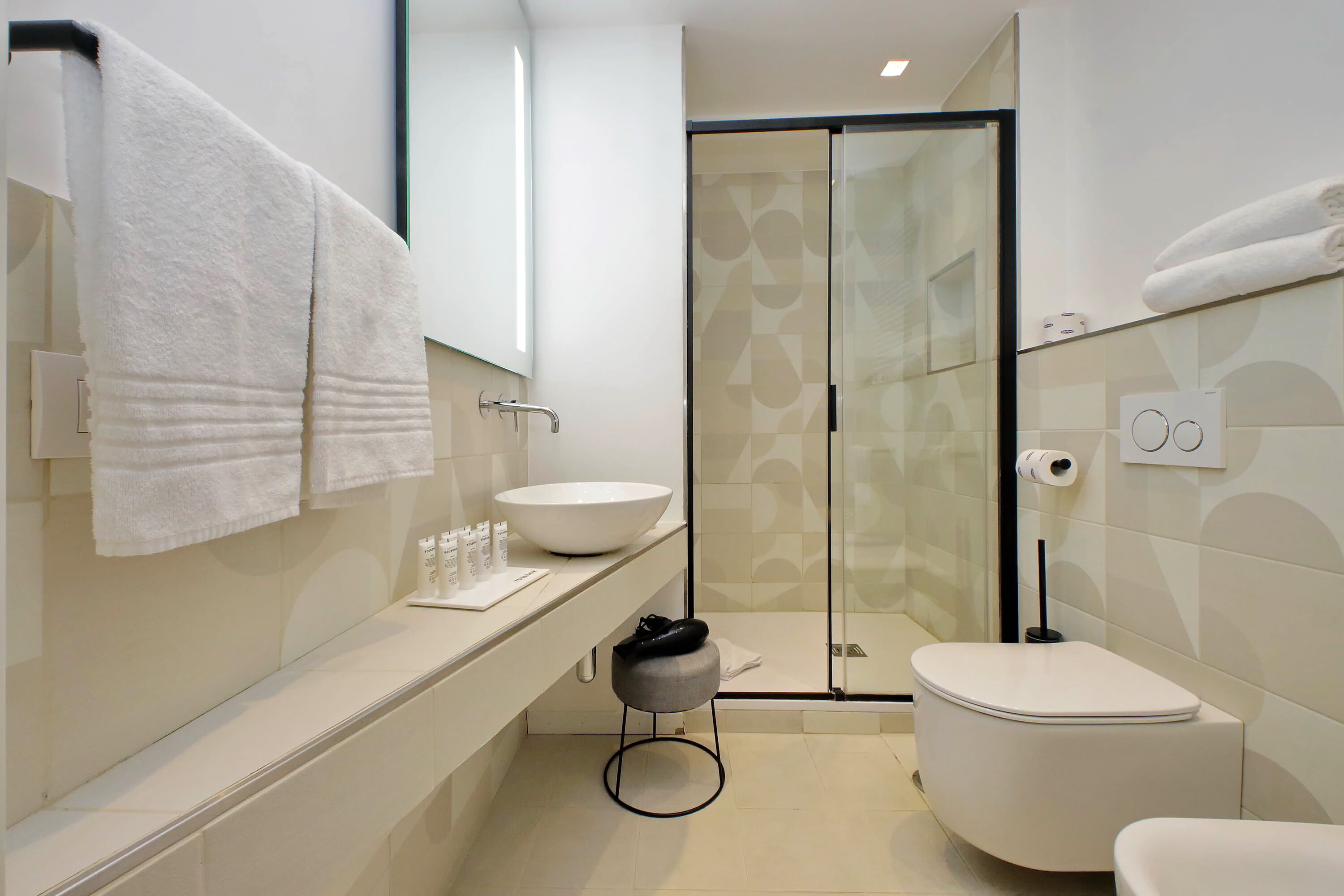 A modern bathroom with a large white sink, a toilet, and a glass shower enclosure.