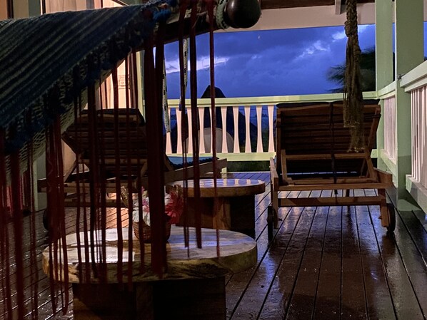 Eine Holzterrasse mit Geländer, Tisch und Stuhl.