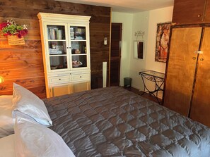 A bedroom with a bed, a wooden wardrobe, a cabinet with glass doors, and a small table with a mirror. - Coco’s Place Bora Bora - CAR INCLUDED (Faanui)