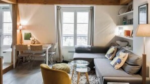 A cozy living room with a sofa, a coffee table, and a dining area with chairs and a table.