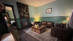 A cozy living room with a fireplace, a sofa, a coffee table, and a patterned rug. - Historical Louisiana Style Home (Dayton)