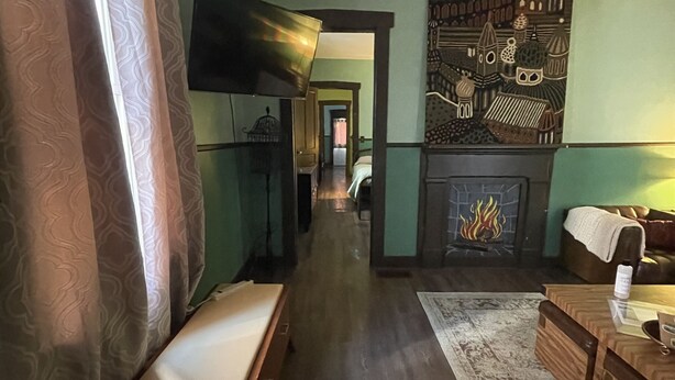 A hallway with a wooden bench, a fireplace, and a TV mounted on the wall. - Historical Louisiana Style Home (Dayton)