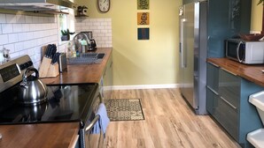 Una cocina con estufa, microondas, refrigerador y un reloj en la pared.