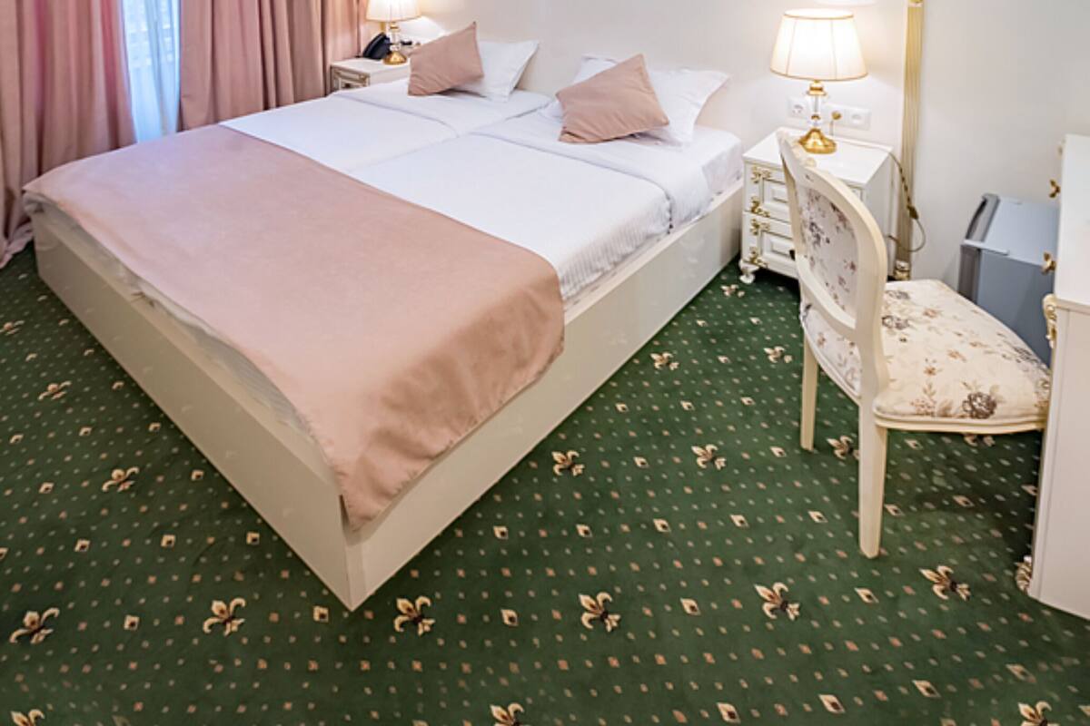 A hotel room with a large bed, a chandelier, a chair, and a nightstand.