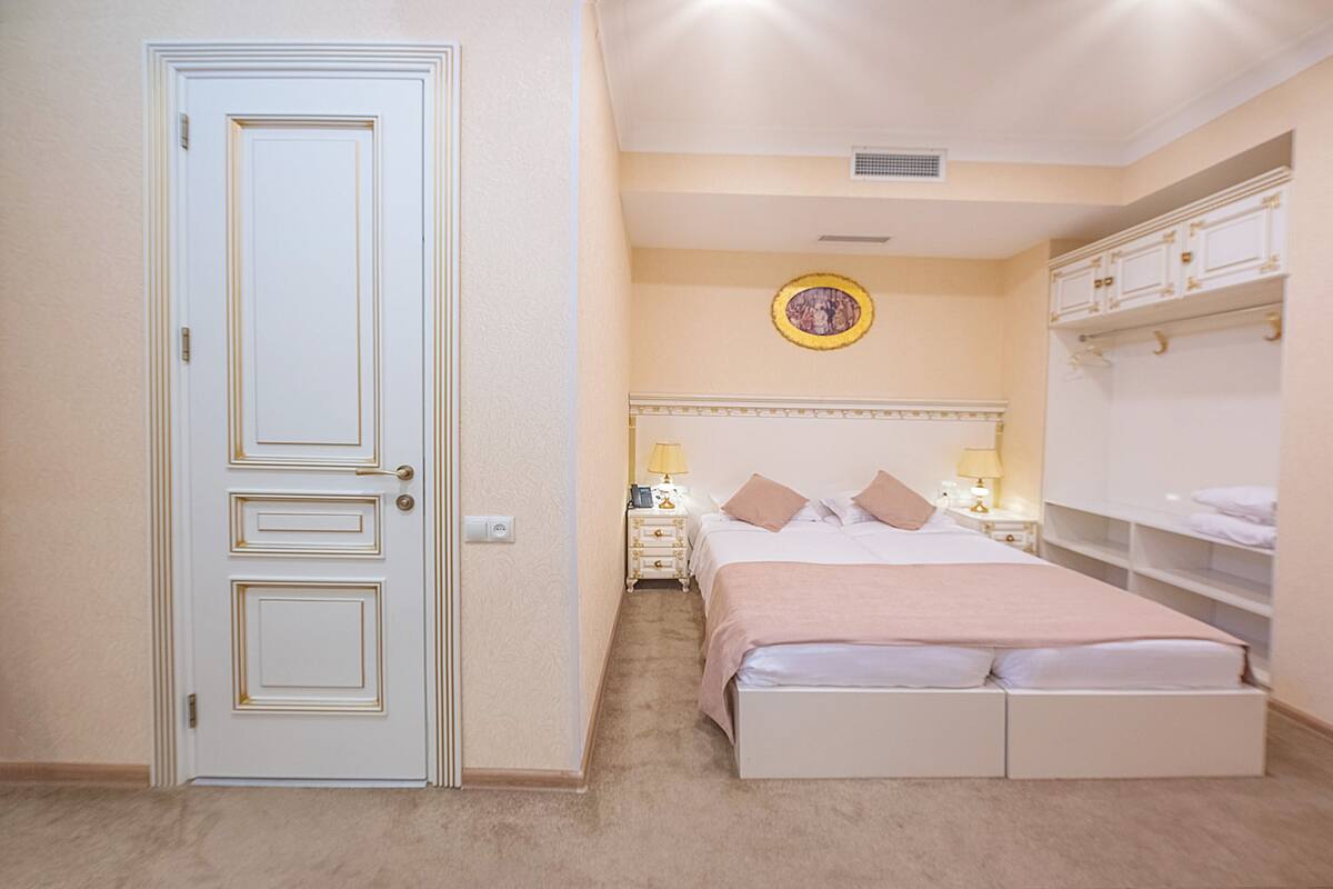 A bedroom with a double bed, bedside tables, a nightstand, a wardrobe, and a door.