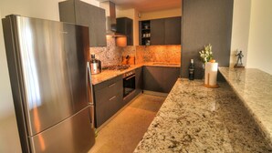 Eine moderne Küche mit Edelstahlgeräten, dunklen Schränken, Granitarbeitsplatten und einem eingebauten Backofen.