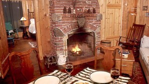 A cozy room with a brick fireplace, wooden furniture, and a dining table set for two.