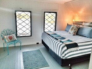 Une chambre à coucher avec un lit, deux fenêtres, une chaise et un tapis.