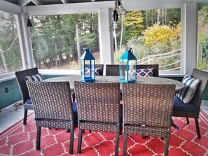 Une terrasse couverte, aménagée avec des meubles en osier et deux lanternes bleues.