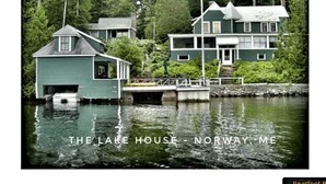 Una casa junto al lago con muelle, rodeada de bosque.