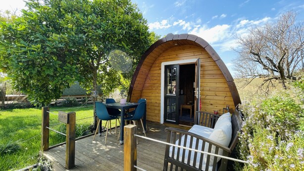 Une cabane en bois dotée d’une terrasse, d’une table avec des chaises et d’un banc.