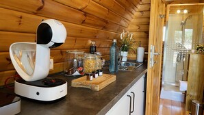 L’intérieur d’une cabane en bois, avec une machine à café, des bocaux remplis de provisions et un évier.