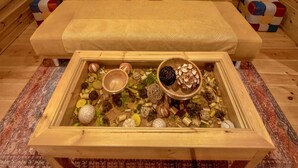 Une pièce chaleureuse avec un banc en bois, un tapis à motifs et un coffre en bois rempli d’objets décoratifs.