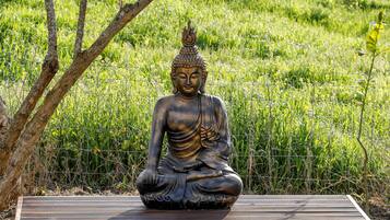 A bronze Buddha statue seated on a wooden platform in a grassy area.
