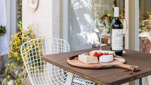 Ein Tisch mit einer Weinflasche, zwei Gläsern und einer Holzplatte mit Käse und Erdbeeren.
