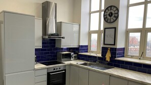 Una cocina moderna con gabinetes blancos, una campana extractora de acero inoxidable, un microondas, un fregadero y un ventanal con vista a la ciudad.