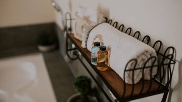 A bathroom vanity area features a shelf with essentials, including a towel, soap, and a potted plant.
