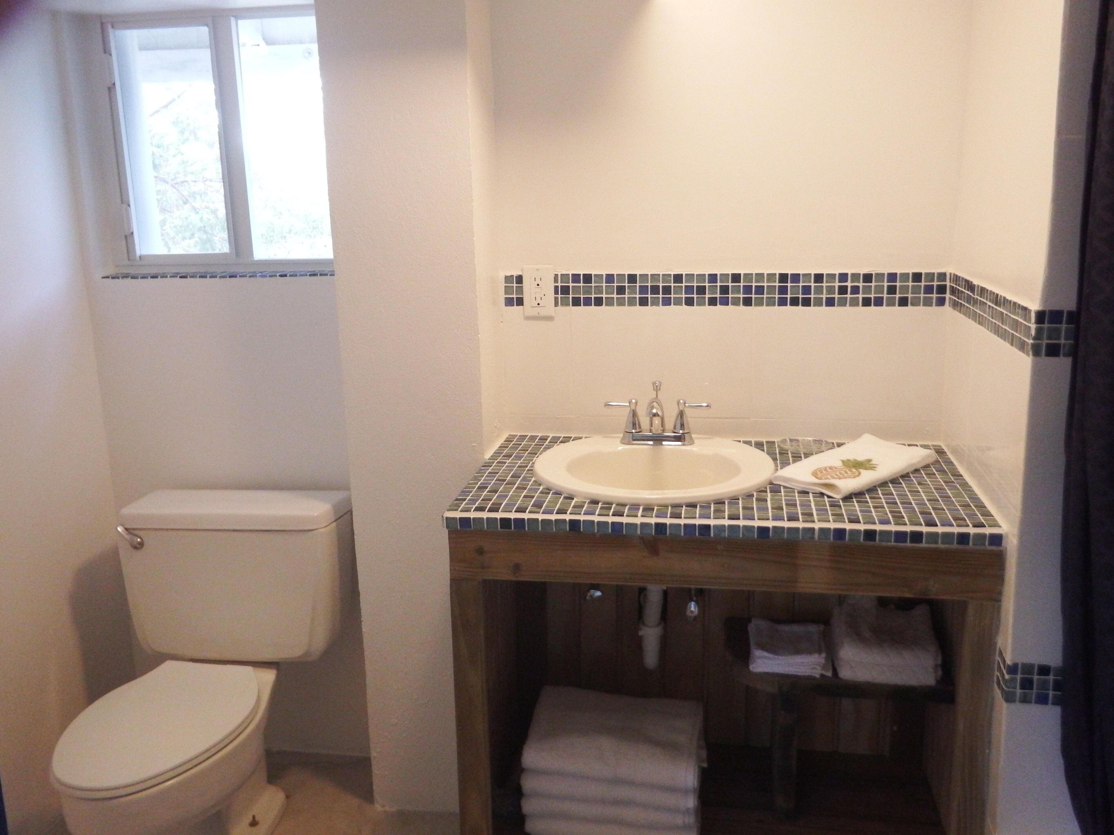A bathroom with a toilet, sink, and tiled backsplash.