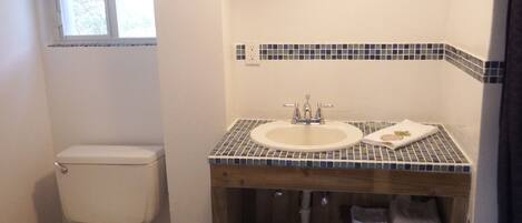 A bathroom with a toilet, sink, and tiled backsplash.