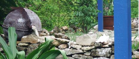 A garden with a stone wall, a large decorative bowl, and various plants.