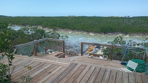 A wooden deck with a hammock and a kayak, overlooking a mangrove-lined waterway. - Historic Island Retreat on Little Exuma (Little Exuma)