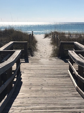 A wooden boardwalk leading to a beach with a clear view of the ocean.